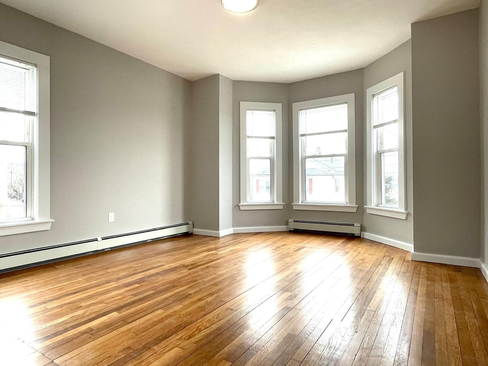 Living room with bay windows and refinished hardwood floors